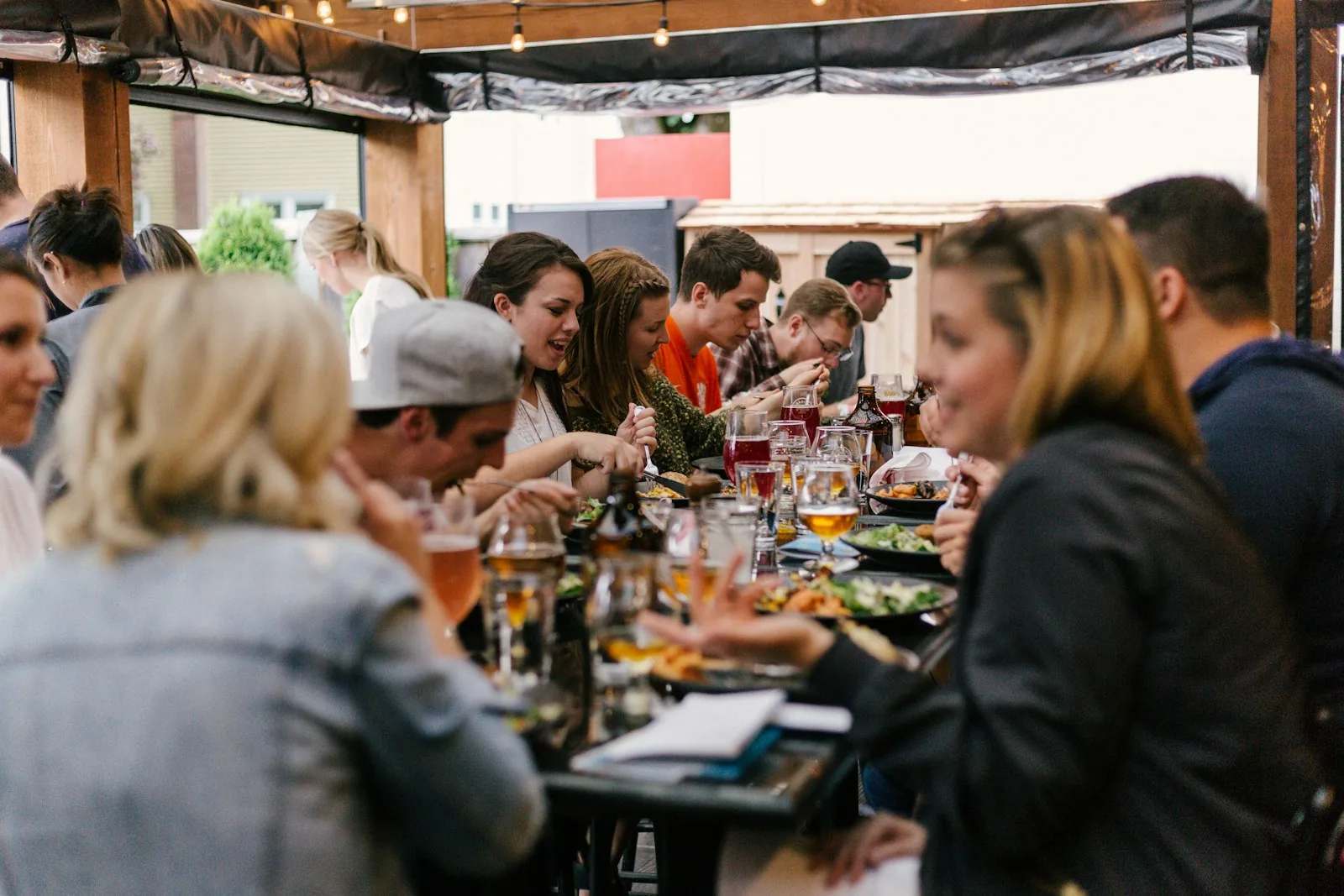 A group of people eating and talking together along a long communal table